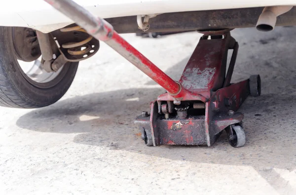 Nära upp skott av gammal röd bil jack och bort hjulet selektiv fo — Stockfoto