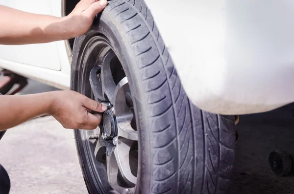 Hands of mechanic pick up the nut of car wheel and tighten — Stock Photo, Image