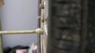 Otomobil tekerleğinin sürgüsünü döndürmek için çapraz düzeltme anahtarı kullanarak mekanikeri yakın çekim yap, alanın derinliğini seç