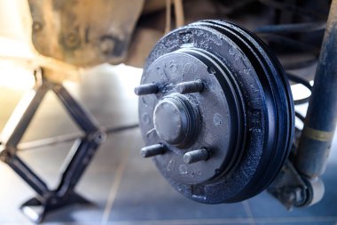 Lastik ve tekerleği söktükten sonra arabanın arka merkezi, fren ve tekerlek sistemi, araba tekerleği değiştirmek için kriko, yakın çekim.