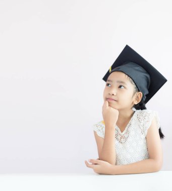 Portre küçük Asyalı kız mezun şapkası takıyor ve mutlulukla gülümsüyor. Eğitim konsepti için fotokopi alanı olan yüzeysel alan derinliği seçin.