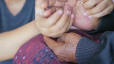 Teselli ve cesaret için yaşlı kadının ellerine dokunan genç bir kadının elleri, aile ve yaş farkı için, seçici bir odak derinliği.