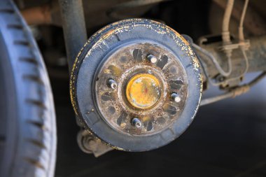 Lastik ve tekerleği söktükten sonra arabanın arka merkezi, fren ve tekerlek sistemi, araba tekerleği değiştirmek için kriko, yakın çekim.