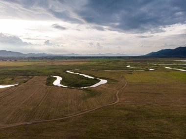 Nehir ve havzanın doğal bir dağa karşı manzaralı manzarası, Drone gürültülü ve tahıl işlenmiş tropikal araziyi vurdu.