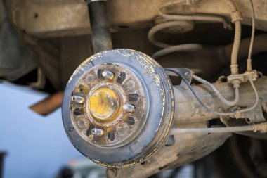 Lastik ve tekerleği söktükten sonra arabanın arka merkezi, fren ve tekerlek sistemi, araba tekerleği değiştirmek için kriko, yakın çekim.