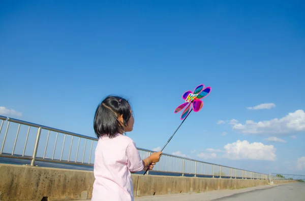 Asian little girl with wind turbine toy in hands — Stock Photo, Image