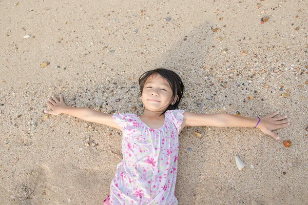 Asiático sorrindo bonito menina deitada na areia da praia. chi tailandês — Fotografia de Stock