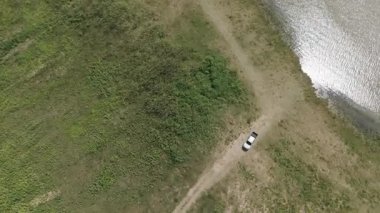 Kırsal bir yolda kırsal araziden geçen bir kamyonetin hava aracı görüntüsü. Doğada seyahat, ulaşım ve özgürlüğün manzaralı görüntüsü