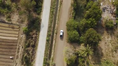 Kırsal bir yolda kırsal araziden geçen bir kamyonetin hava aracı görüntüsü. Doğada seyahat, ulaşım ve özgürlüğün manzaralı görüntüsü