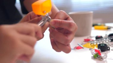 Bir çocuğun üç boyutlu baskılı parçalardan yapılmış DIY robotu monte edişini, aile bağlarını, STEM öğrenmesini ve evdeki teknolojiyi kullanarak yaratıcı gelişimi kaydetmesini kapatın.