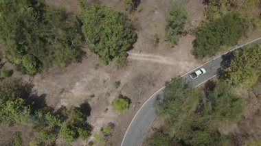 Kırsal bir yolda kırsal araziden geçen bir kamyonetin hava aracı görüntüsü. Doğada seyahat, ulaşım ve özgürlüğün manzaralı görüntüsü