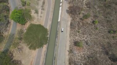 Kırsal bir yolda kırsal araziden geçen bir kamyonetin hava aracı görüntüsü. Doğada seyahat, ulaşım ve özgürlüğün manzaralı görüntüsü