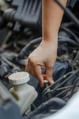 Yağ seviyesini kontrol etmek için motor yağı çubuğunu çeken, atölye ortamında araç bakımını ve motor bakımını ön plana çıkaran bir kadının eli..