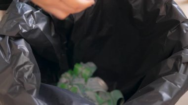Modern evde plastik şişeyi geri dönüşüm kutusuna koyan kişi. Atık ayıklama, sürdürülebilirlik ve çevresel sorumluluk kavramı