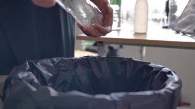 Modern evde plastik şişeyi geri dönüşüm kutusuna koyan kişi. Atık ayıklama, sürdürülebilirlik ve çevresel sorumluluk kavramı