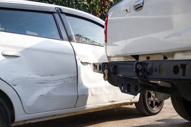 Trafik kazasından sonra hasarlı beyaz arabanın yakın çekimi, yan çarpmayı ve vücut hasarını gösteriyor. Araba sigortası talepleri, araç denetimi, trafik kazası ve otomotiv risk değerlendirmesi konsepti