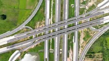 Çevresi yeşil tarım arazisiyle çevrili çok katmanlı yollar ve eğimli rampalarla modern otoyol kavşağının havadan görünüşü, ulaşım altyapısı, kentsel gelişim ve karayolu planlaması sergileniyor.