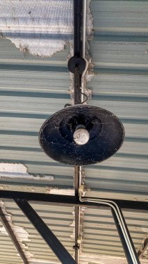 Tavanda asılı duran siyah kolye metal kaplama çatısı, endüstriyel iç aydınlatma ve minimal mimari detay