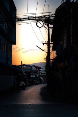 Şehir elektrik hatları gün batımına karşı siluet, şehir altyapısı ve soyut geometri günlük yaşam ve akşam atmosferini yakalıyor.