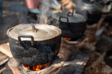 Geleneksel odun sobası ateşin üzerinde metal tencereyle pişirme, yakacak odun kullanarak kırsal mutfak, sürdürülebilir yaşam tarzı, basit yaşam ve geleneksel yemek hazırlama