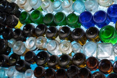 Soyut bir arkaplan olarak beyaz bir duvarda çok renkli şişeler