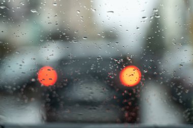 Araba ışıkları yağmur damlalarında camın içinden geçer.