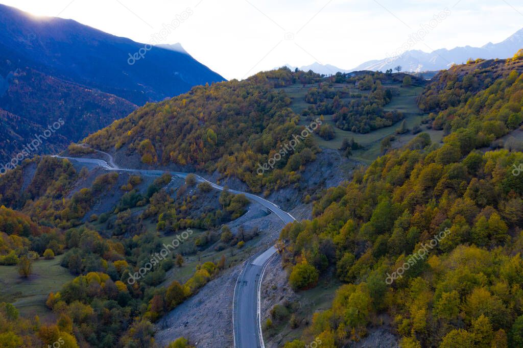 Winding road in the mountains, autumn forest view from a drone