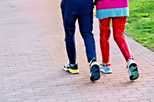 a man and a woman in colorful shoes are walking in the park