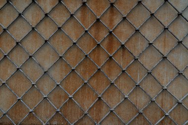 Beton bir duvarın arka planında eşkenar dörtgen şeklinde metal kafes.