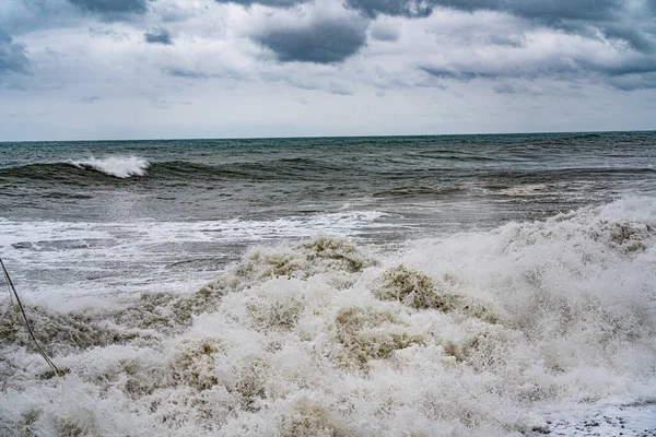 曇った空を背景に嵐の海に波を衝突させ — ストック写真