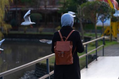 Sırt çantalı bir kız köprüden geçiyor.