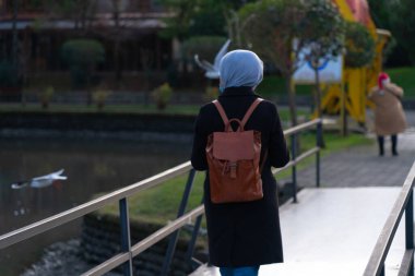 Sırt çantalı bir kız köprüden geçiyor.