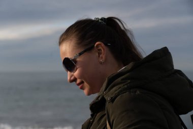 Sırt çantalı bir kız kışın kumsalda yürüyor.