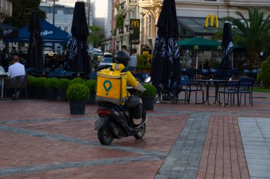 Batumi, Georgia - June 07, 2021: Courier of Glovo company on a motor scooter clipart