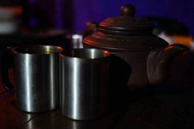 Metal bardaklar metal bir çaydanlıkla masanın üzerinde duruyor.