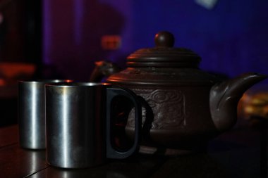 Metal bardaklar metal bir çaydanlıkla masanın üzerinde duruyor.