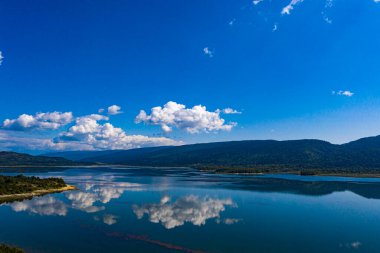 River surrounded by green forest clouds are reflected in the water