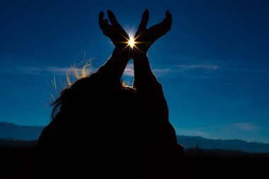 Kız elleriyle güneşte şekil veriyor.