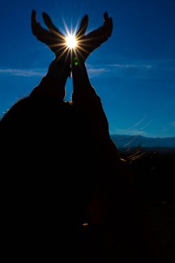 Kız elleriyle güneşte şekil veriyor.