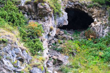 Dağlarda, yeşilliklerin arasında bir mağara.