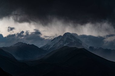 Bulutlu bir gökyüzünün arka planındaki gri dağ