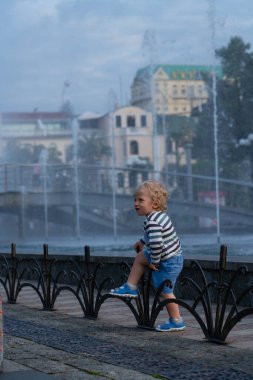 Batumi, Gürcistan - 17 Haziran 2021: Parkta bir çocuk şarkı söyleyen çeşmelerin arka planında