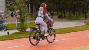 Kız yol boyunca bisiklet sürüyor.