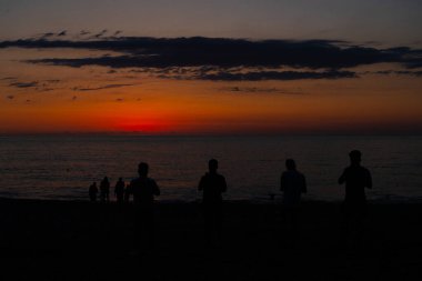 İnsanlar gün batımının arka planında, denizde.