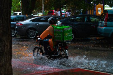 Batumi, Georgia - 14 Temmuz 2021: Kurye yağmurda motosiklet sürüyor