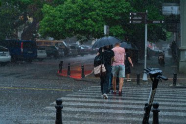 Batumi, Gürcistan - 14 Temmuz 2021: Bebek arabalı erkekler şemsiye altında yürüyor