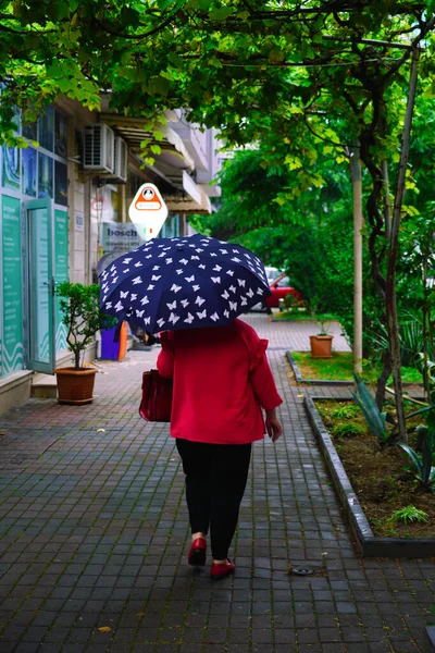 2021年6月30日 佐治亚州巴统 一位拿着雨伞走在人行道上的妇女 — 图库照片
