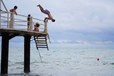 Batumi, Gürcistan - 11 Ağustos 2021: Erkekler iskeleden denize atlıyor