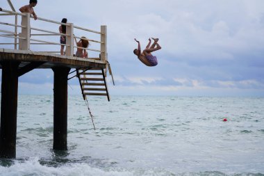 Batumi, Gürcistan - 11 Ağustos 2021: Erkekler iskeleden denize atlıyor