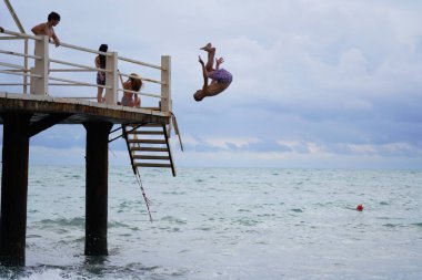 Batumi, Gürcistan - 11 Ağustos 2021: Erkekler iskeleden denize atlıyor